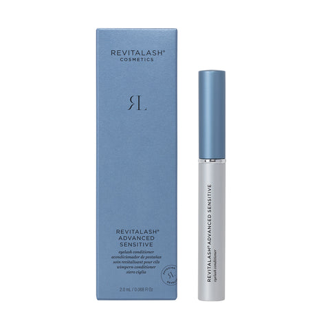 A box and a tube of RevitaLash Advanced Eyelash Conditioner and Enhancing Serum Sensitive (2.0mL 3 Mo. Supply) are displayed, featuring blue packaging with silver text and a white tube capped in silver, highlighting branding and essential eyelash health info.