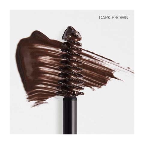 A RevitaLash Hi-Def Brow Gel wand, featuring dark brown gel, is artfully smeared on a light background to display its rich color and texture. The precision brush ensures impeccable styling for brows. Top right corner reads “Dark Brown.”.