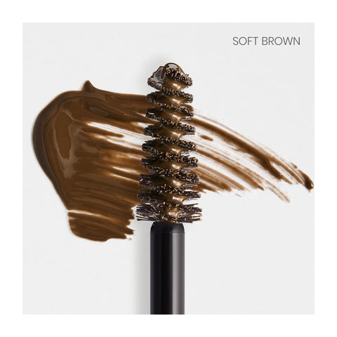 The RevitaLash Hi-Def Brow Gel, available in 3 colors, features a precision styling brush coated in soft brown makeup with a brown smear on a white surface. Soft Brown is displayed in the top right corner, ideal for setting eyebrows.