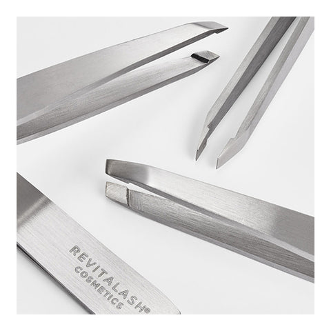 Close-up of four RevitaLash Precision Tweezers on a light gray background, perfect for groomed brows, with RevitaLash inscribed. Each professional-grade metallic tweezer offers a unique tip design for various tasks.
