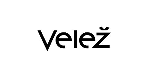 White text Velež BY VESNA is centered on a smooth purple background, with Velež in large font and BY VESNA below it in smaller, lighter text.